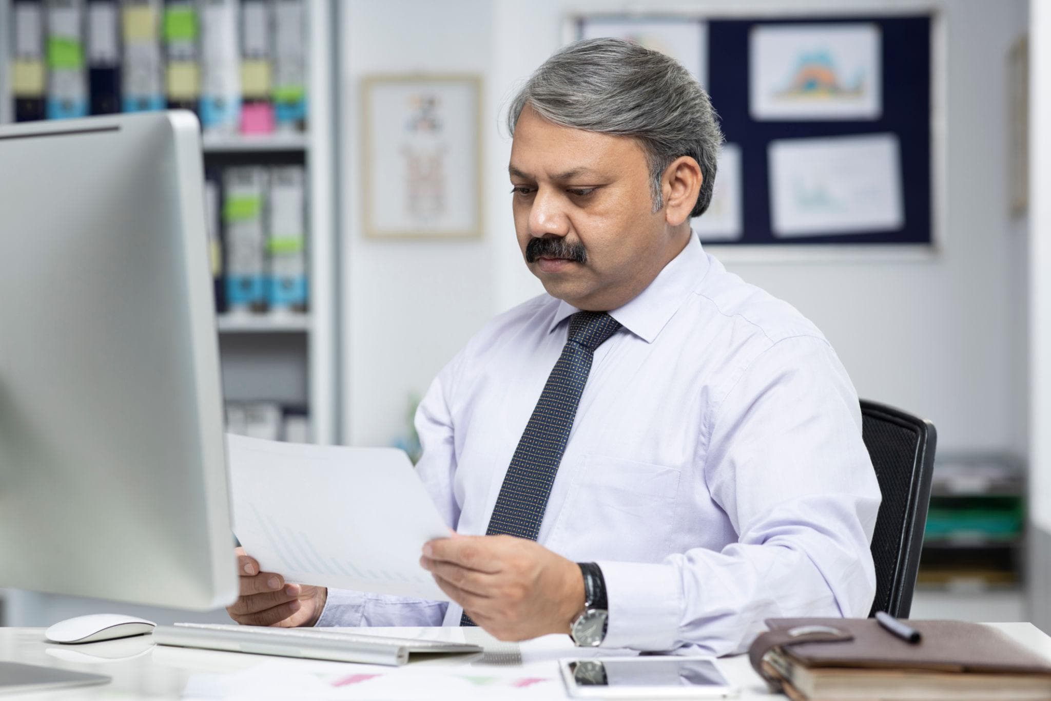 Indian business owner reviewing financial documents at an office desk