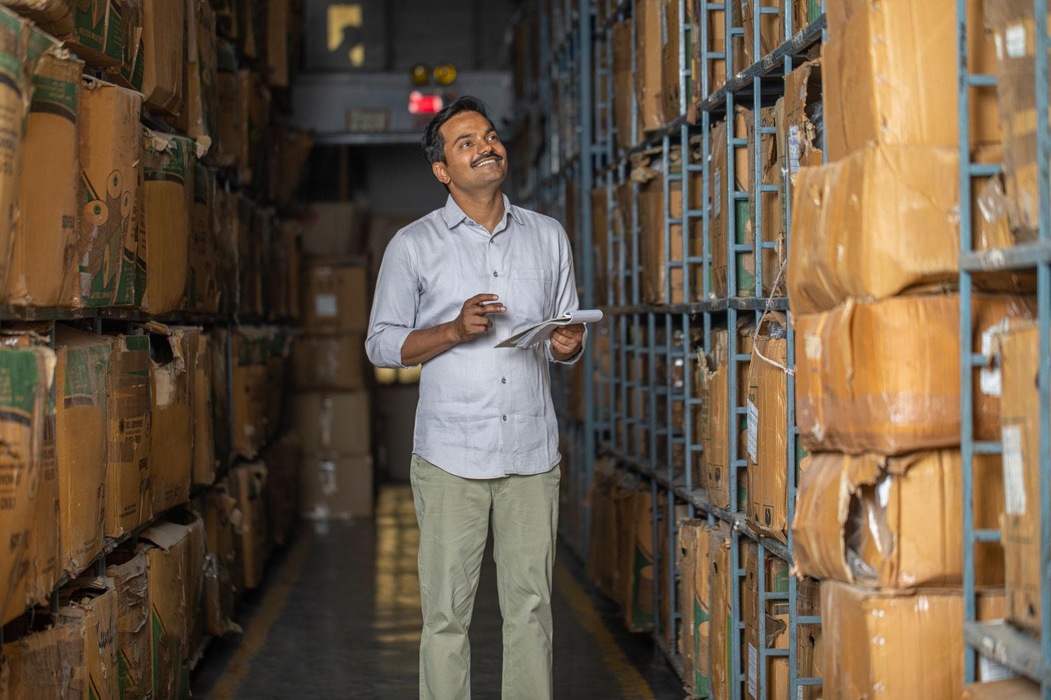 Indian warehouse manager checking inventory between storage shelves